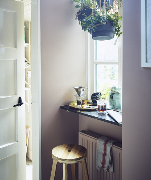 Стол пред прозорец с висящи растения и прибори за приготвяне на кафе